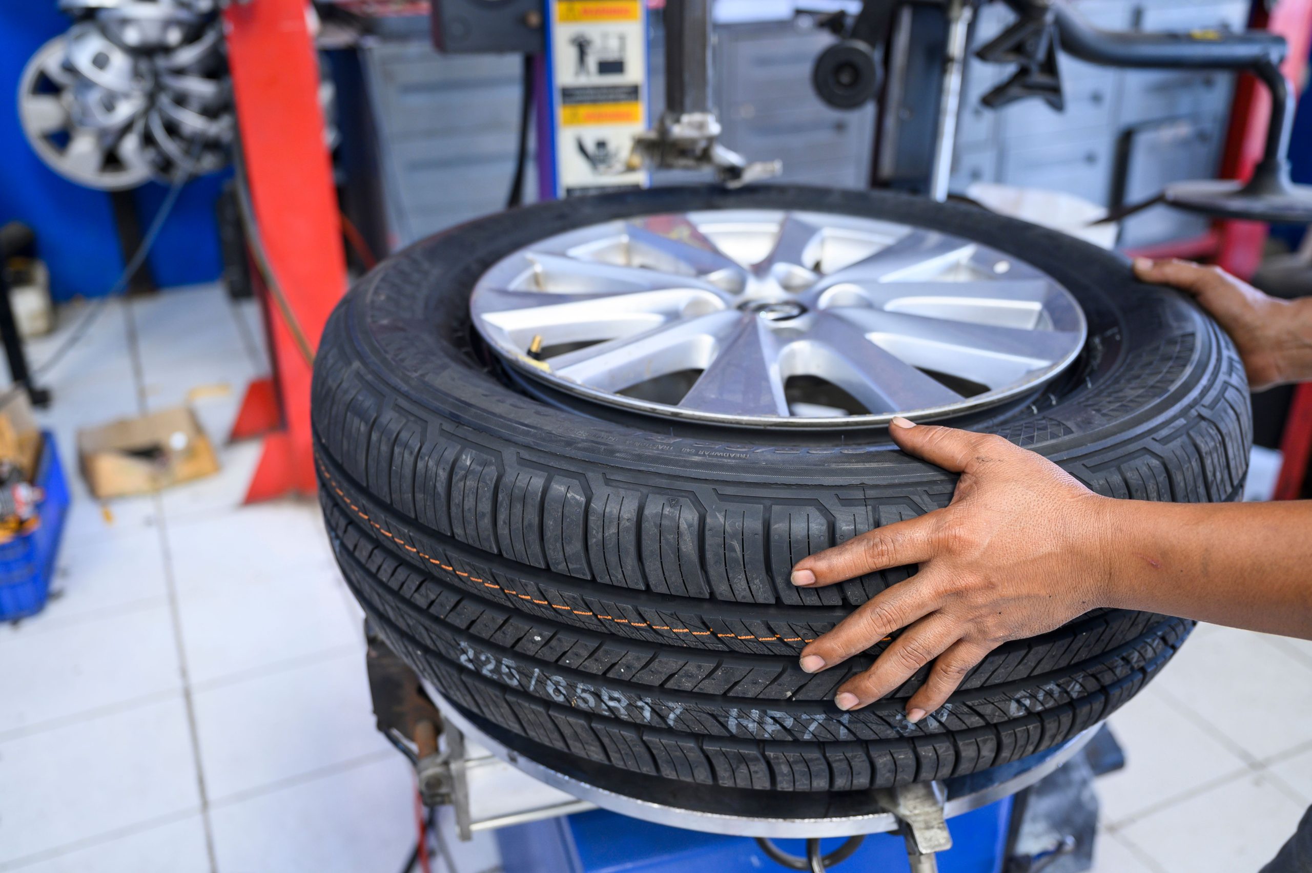 Mechanic installing tire on car wheel in tire shop